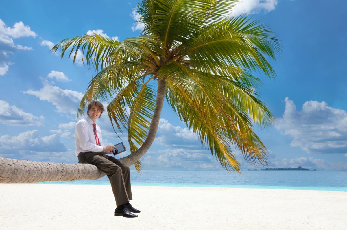 man with tablet pc sitting on palm tree 137388439